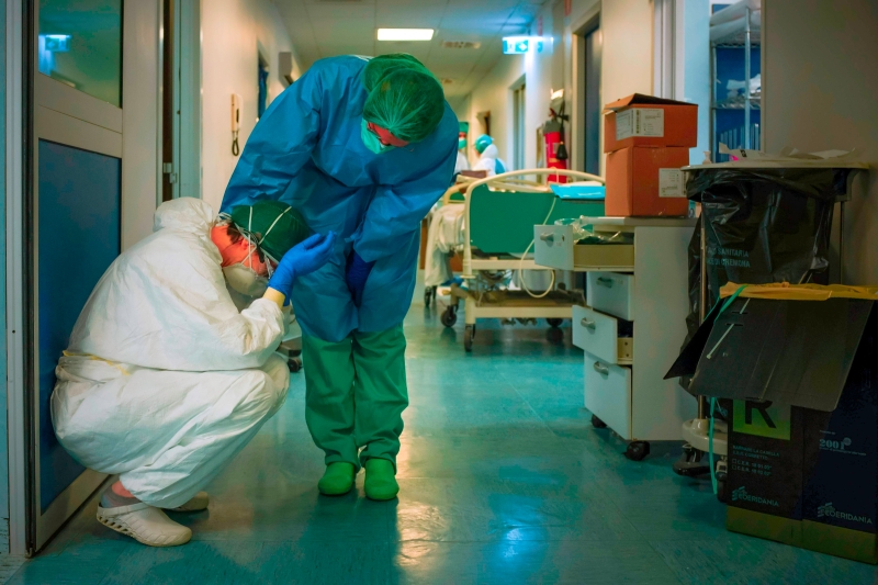 在意大利重灾区伦巴第的一家医院内，一医务人员在换班时，安慰另一名同事。（法新社照片）