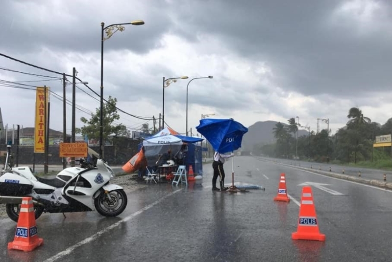 即使狂风暴雨把遮阳伞都吹歪了，警员仍需站稳岗位，在路障处执勤。
