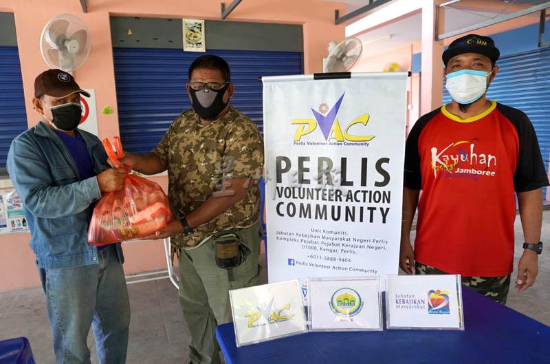 玻璃市志愿者行动社区主席依芬迪（中）移交日用品给其中一名受惠者。