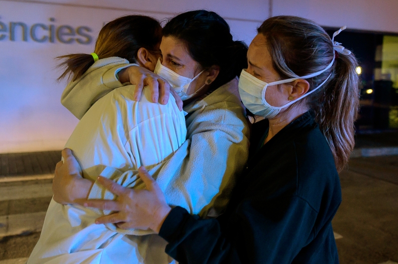 在这个艰难时刻，前线医护人员互相拥抱，勉励彼此。（图：法新社）