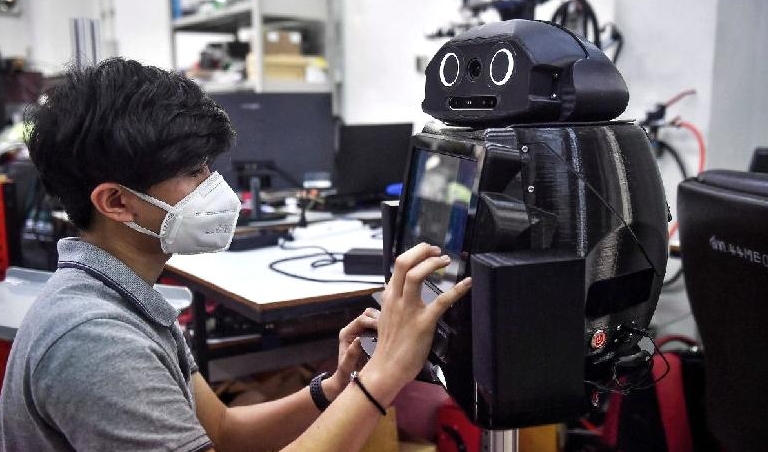 An engineering student configures a medical robot modified to screen and observe COVID-19 patients at the Regional Center of Robotics Technology at Chulalongkorn University in Bangkok. AFP