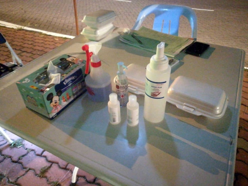 小帐棚内的桌面，陈放著饭盒、盒装纸巾、消毒喷剂和搓手液。