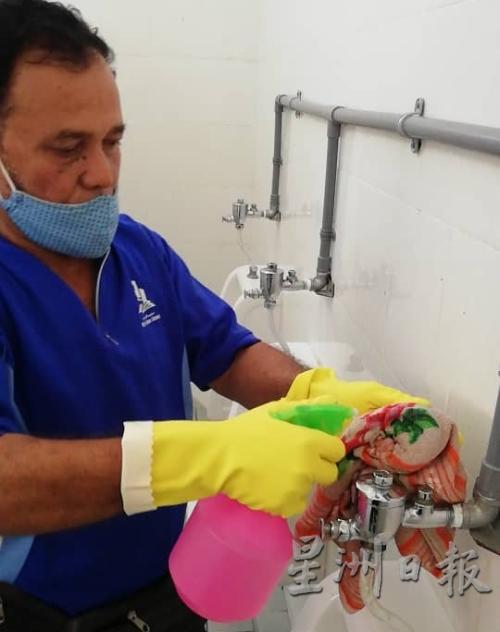 一名清洁工人正按照市议会卫生组官员的指示，以混有肥皂和漂白水的清洁剂，清洗巴刹公厕。（图：星洲日报）