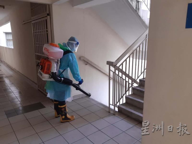 斯里沙登义务消防队队员为公寓的公共区域进行消毒。（图：星洲日报）