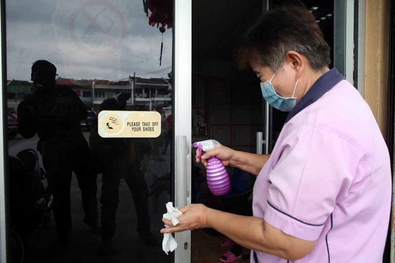 为防止冠病入侵森华医疗中心洗肾部（史里肯邦安分院），清洁工人对玻璃门进行消毒。
