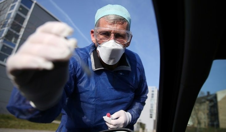 German doctor Michael Grosse takes a sample from a car driver at a drive-through testing point for the coronavirus in Halle, eastern Germany. AFP