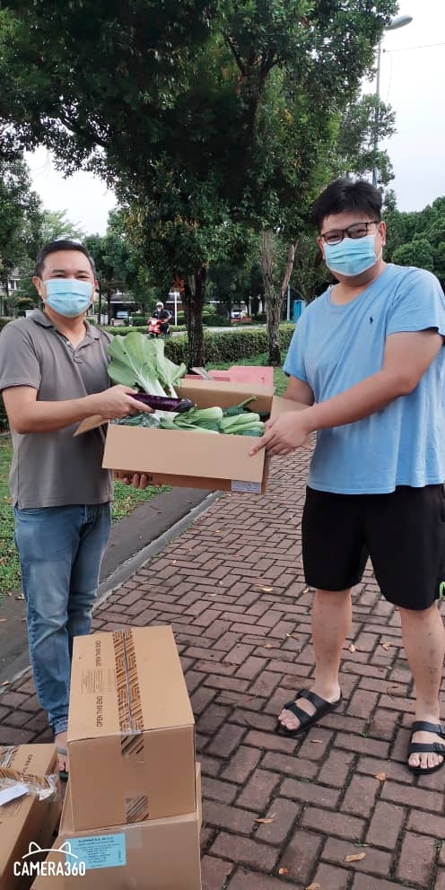 黄思汉（左）派发蔬菜箱给居民王伟征。