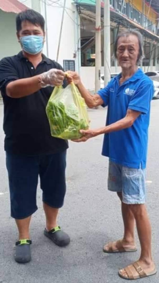 吴国忠（左）将蔬菜送给有需要的老人家。