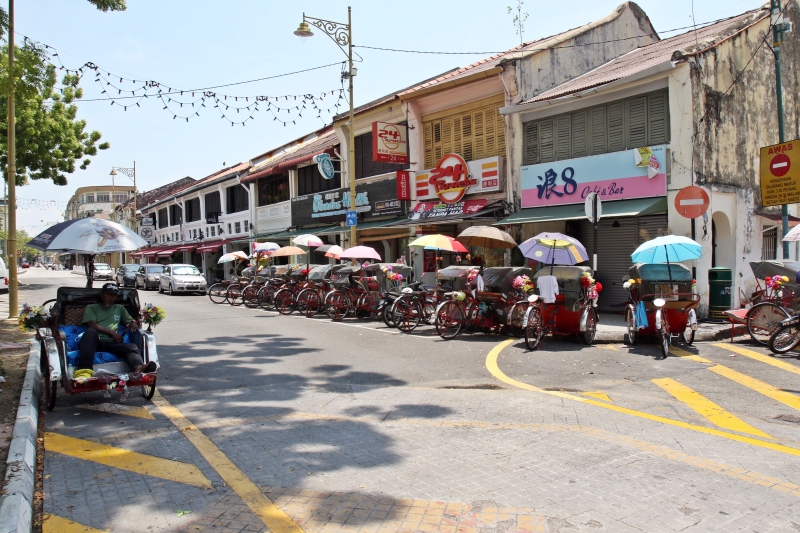 槟岛乔治市：旅游区区可见一整排的三轮车停在路旁，零收入的车夫无奈地坐在三轮车上等时间滴滴答答地过去。