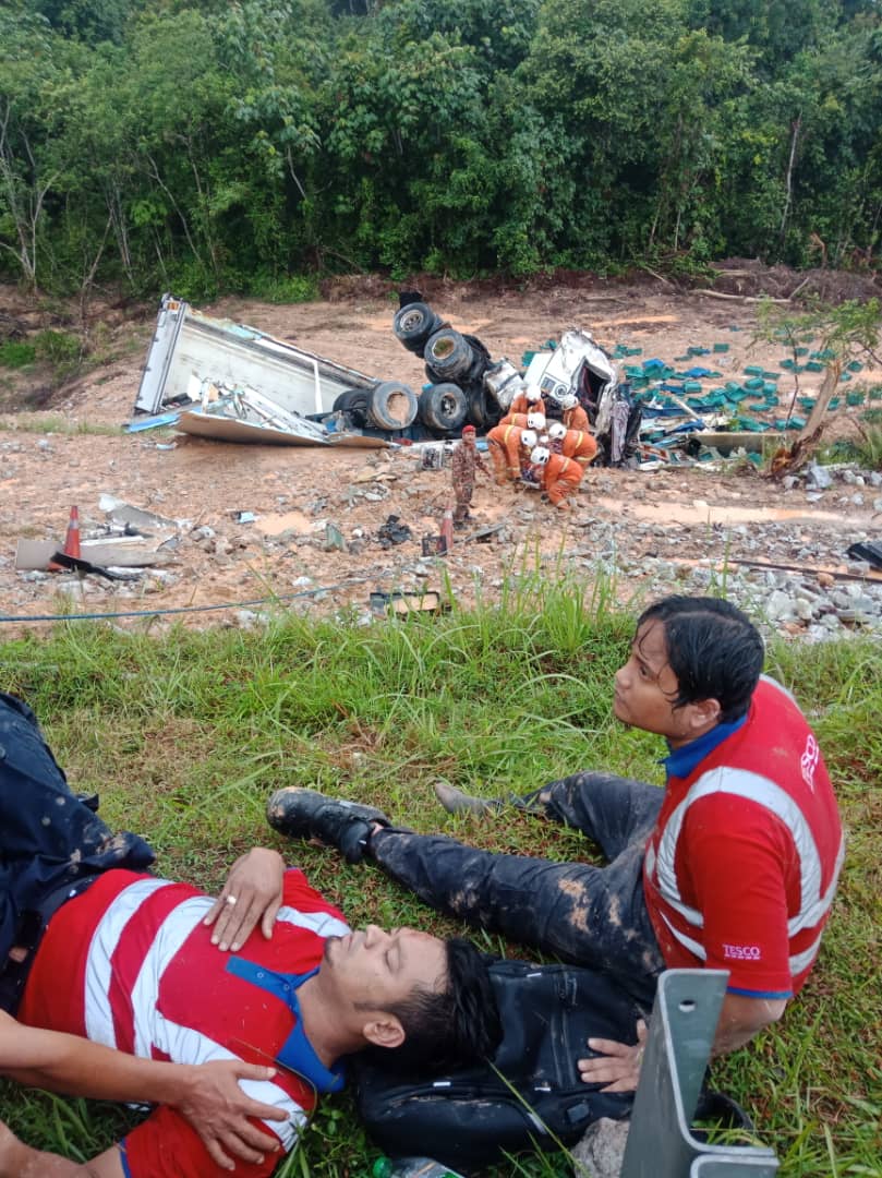 两名伤者坐在山坡上等待救护车将他们送院治疗。