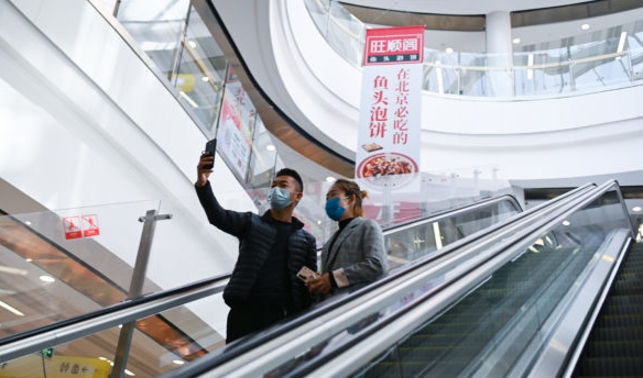A couple wearing face masks take a selfie in a mall in Beijing. AFP