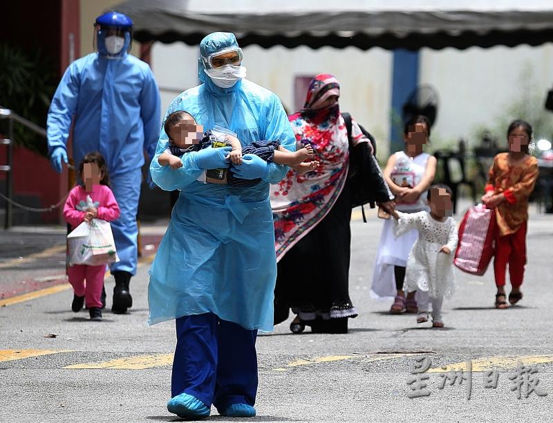 一名医护人员怀抱疑患冠病的婴儿准备送医；后排为穆斯林妇女和她的4名年幼女儿。