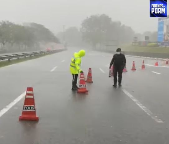 2名警员冒雨整理好被狂风吹倒的安全三角锥。（Friends Of PDRM视频截图）