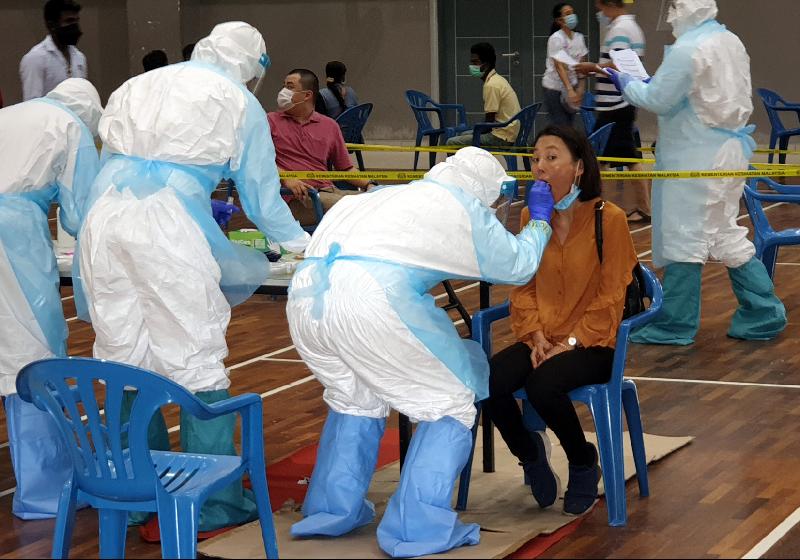 卫生部官员在吉隆坡峇都慕达社区礼堂为小贩们进行冠病检验。