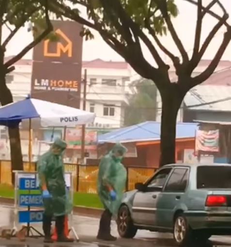穿着雨衣的警员不惧风雨，在路障一一排查轿车。（Friends Of PDRM视频截图）