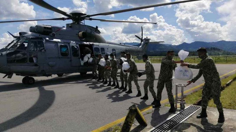 空军将粮食送抵内陆郊外地区后，将粮食从直升机内搬运下机。
