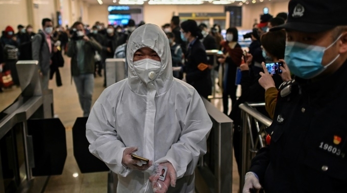 Passengers in protective suits arrive at Hankou station to board the train leaving the city. AFP