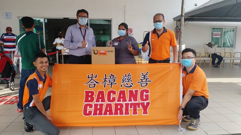 峇樟慈善基金关爱队主任苏楠福 (右一站者) 移交防护面罩给东方医院。