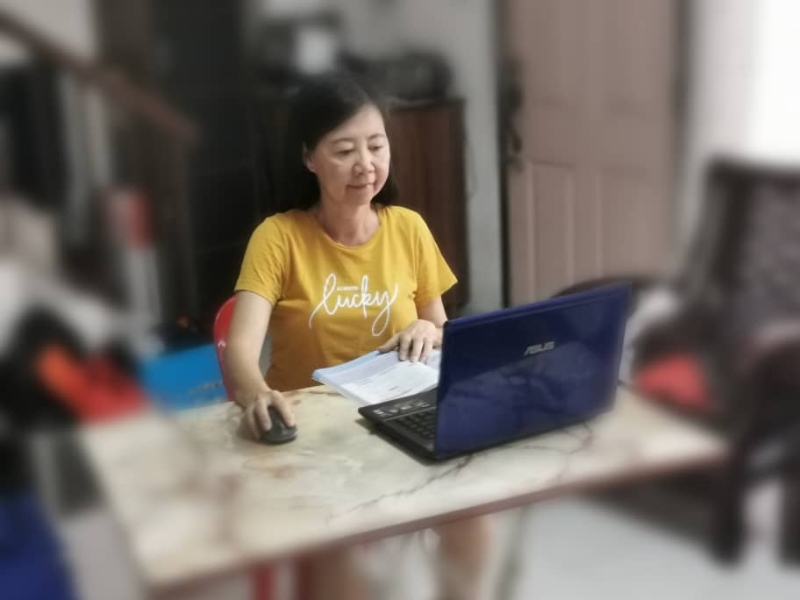 一名教师在家中忙著通过电脑布置作业，让学生通过线上教学掌握知识。

