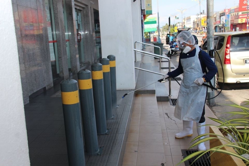 喷洒消毒药物的工作人员今天继续在万津市区展开消毒活动，在商业区店前喷洒消毒。