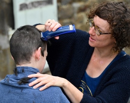 A woman gives her son a haircut outside their home in Brittany, France. AFP A woman gives her son a haircut outside their home in Brittany, France. AFP