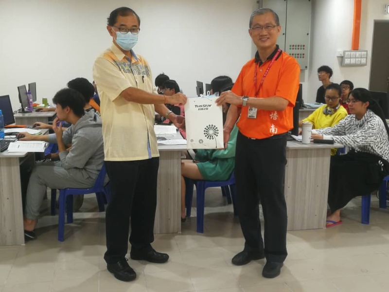 马汉顺（左）赠送500片口罩给培南独中寄宿生，由梁炳初校长代表接领。