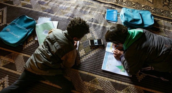 Young pupils follow a lesson on a mobile phone at a camp for displaced Syrians in Kafr Yahmoul in northwestern Idlib province. AFP Young pupils follow a lesson on a mobile phone at a camp for displaced Syrians in Kafr Yahmoul in northwestern Idlib province. AFP