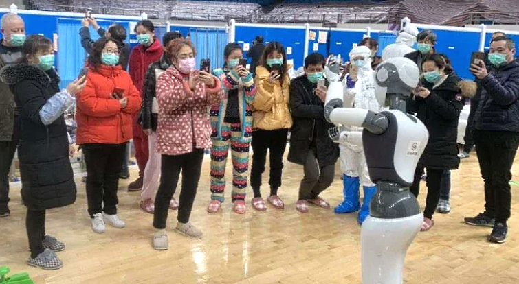 CloudMinds handout image shows people looking at a robot during a trial at a field hospital in a Wuhan sports stadium. AFP CloudMinds handout image shows people looking at a robot during a trial at a field hospital in a Wuhan sports stadium. AFP