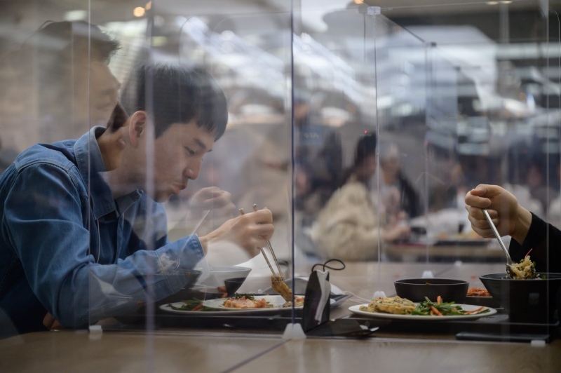 在首尔的现代信用卡公司以透明塑料板分割餐桌，以保护用餐的员工。（法新社照片）
