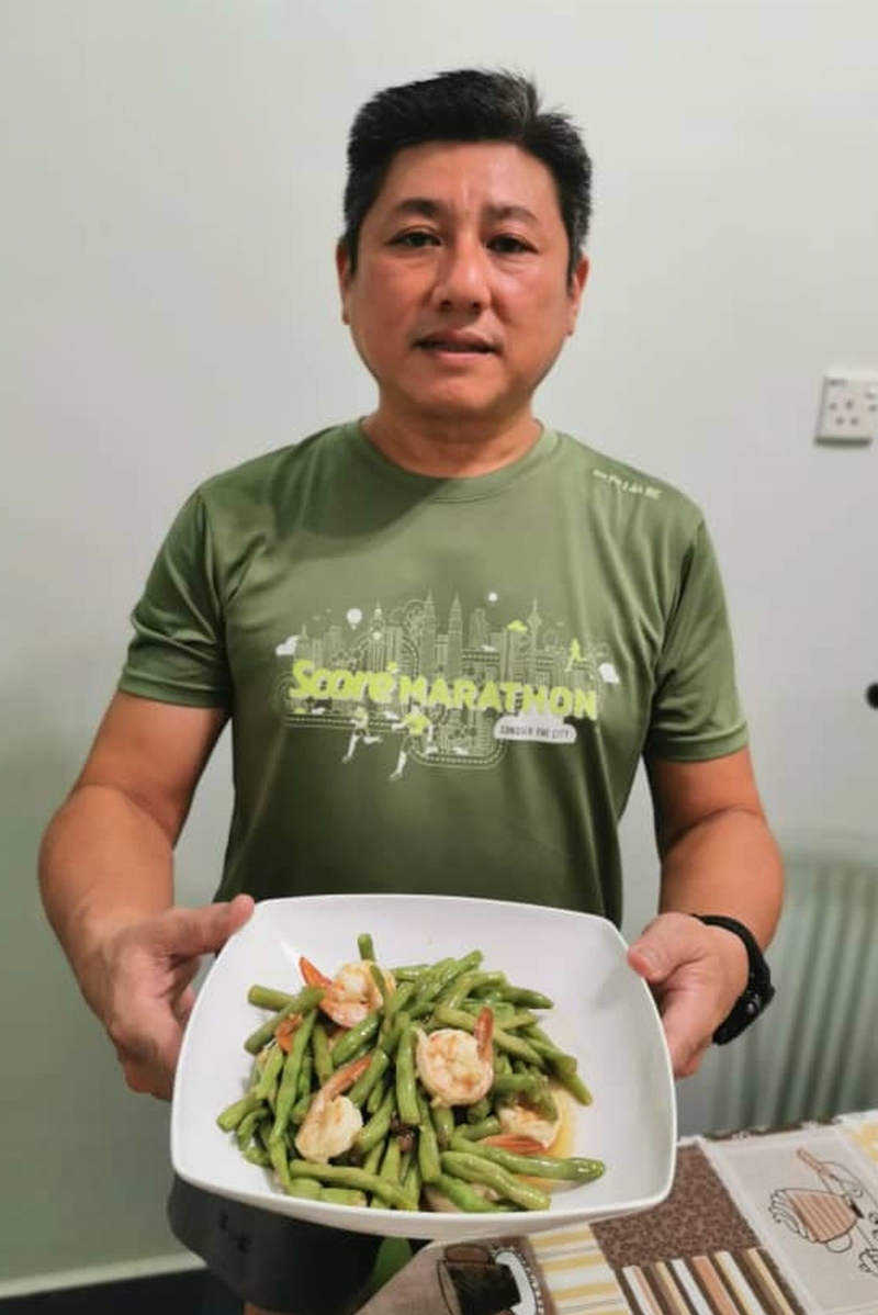 不曾下厨的林汉华展示自己炒出的虾仁四季豆。