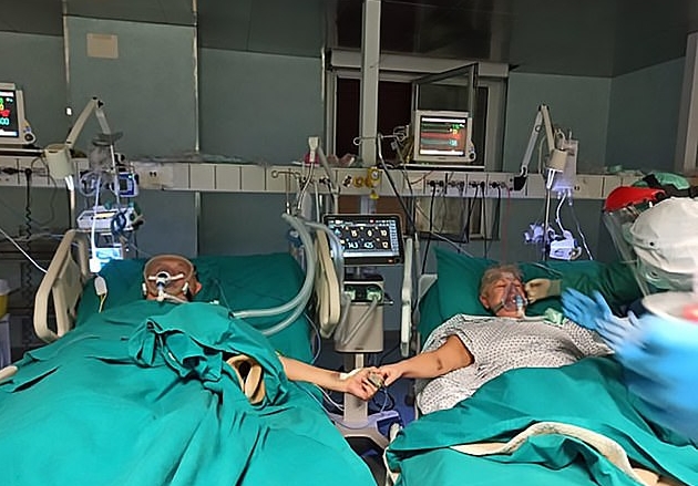 71岁的珊德拉及73岁的吉安卡罗，分别躺在两张病床上，头部各别都接上了呼吸器，口部也罩了氧气罩，两人各自伸出手握住了对方的手。(图：互联网）