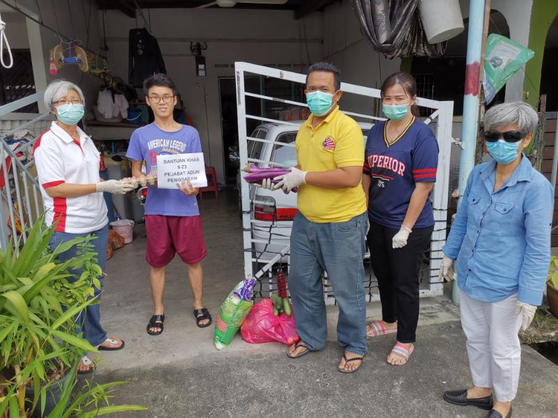 颜碧贞（左一）发放物资予峇株巴辖其中一户有需要的家庭。