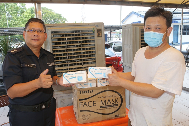 姚永昌（右）移交1000片口罩给怡保警区总部，由诺丁（左）接收。