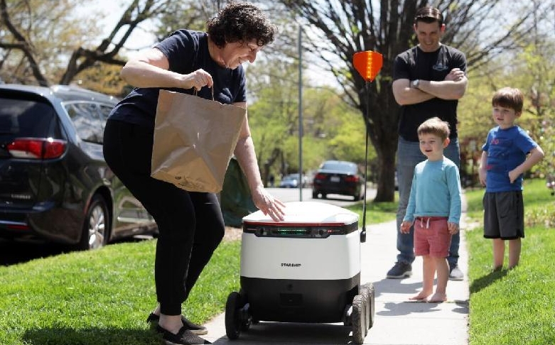 A resident takes out her order from a Starship Technologies delivery robot in the Chevy Chase neighborhood of Washington, DC. AFP A resident takes out her order from a Starship Technologies delivery robot in the Chevy Chase neighborhood of Washington, DC. AFP