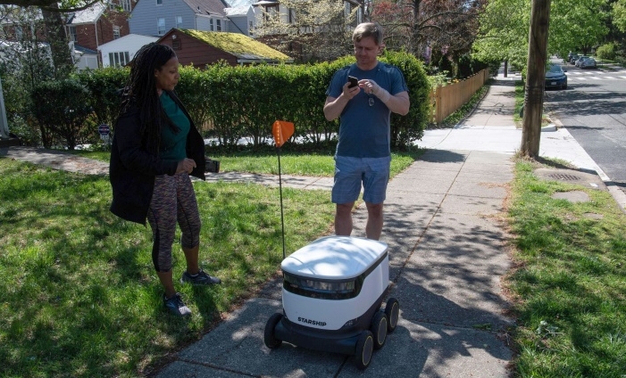 Kimmo Kartano uses his smartphone to open a food delivery robot from the Broad Branch Market grocery store in front of his house in the Chevy Chase neighborhood of Washington, DC. AFP Kimmo Kartano uses his smartphone to open a food delivery robot from the Broad Branch Market grocery store in front of his house in the Chevy Chase neighborhood of Washington, DC. AFP