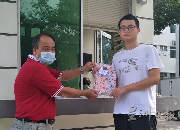 颜文伟（左）把中国驻槟城总领事馆捐赠的个人防护装备移交给就读于生物医学系的中国留学生叶凌江。（图：星洲日报）