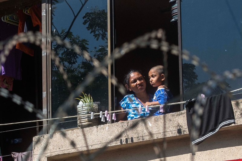 一名妇女抱着孩子在窗口眺望，对于突然“受困”感到无奈。