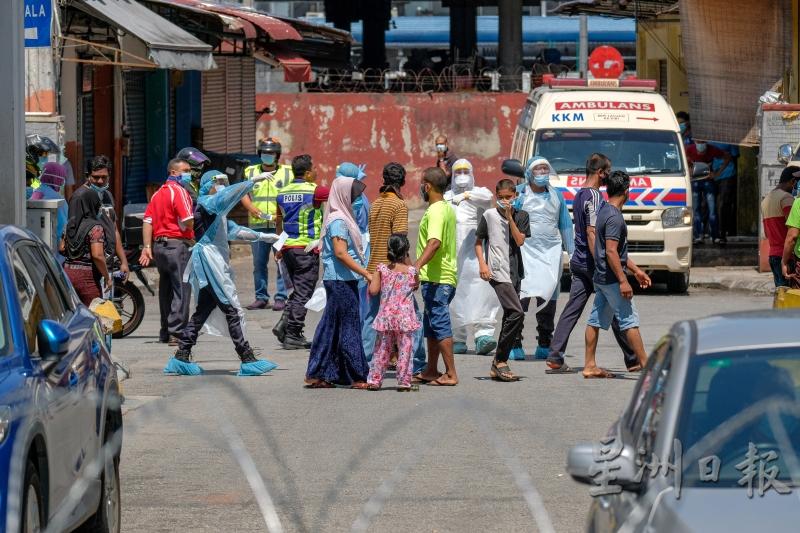 住在吉隆坡批发公市附近店屋的居民在卫生部官员的带领下，前往进行冠病检测。