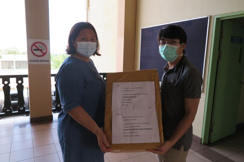 星洲日报民都鲁办事处主任梁安妮（左）移交口罩予颜程荣医生。
