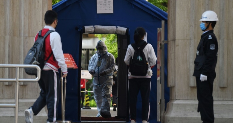 An official in a hazmat suit greets students returning to classes as schools re-open in Beijing. AFP An official in a hazmat suit greets students returning to classes as schools re-open in Beijing. AFP