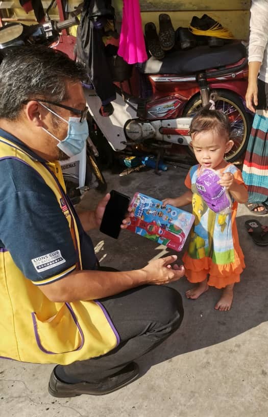 陈绍华（左）赠送援助品时也送上玩具，让小朋友爱不释手。