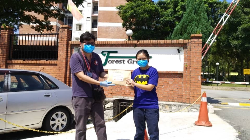 黄志宏（左）把防疫健康包移交给中国留学生。