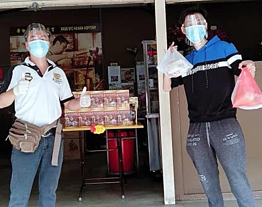 冯文威（右）从吴金鸿手中接取打包食物和饮料，他还获得赠送脸罩。

