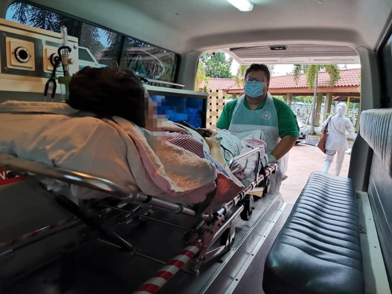 参与冠病医疗辅助行动（#OpsMASCOV）的成员，在为病患转移医院时，将病患推入救伤车内。