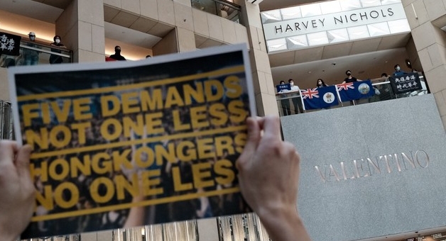 A pro-democracy protester holds up a placard at a shopping mall during a A pro-democracy protester holds up a placard at a shopping mall during a