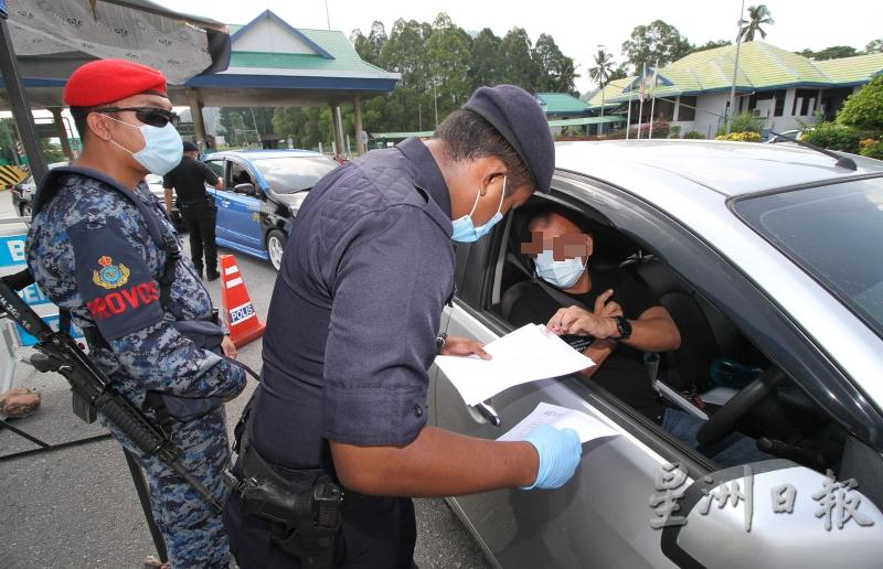 军警逐一严格检查每个进入和离开收费站的车辆，确保他们是获准上路的。（图：星洲日报）