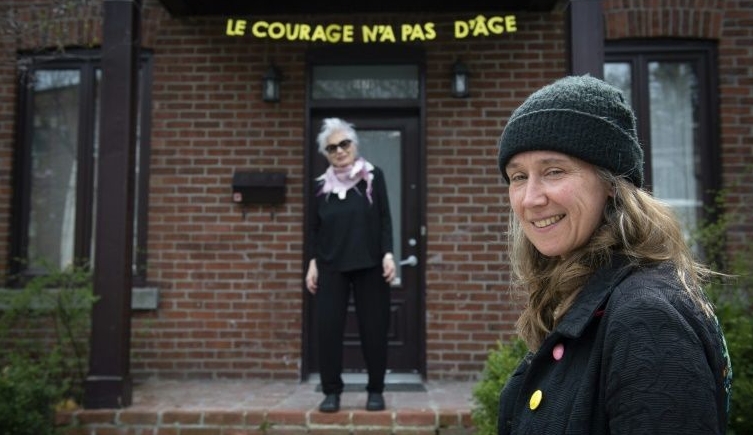 Artist Patsy Van Roost (R) poses with actress Louise Latraverse and her banner 