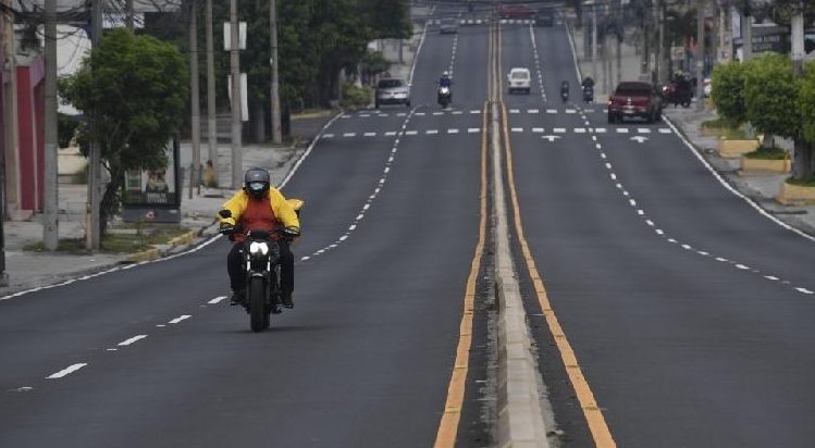 A fast food delivery motorcyclist rides along an empty street in San Salvador. AFP
