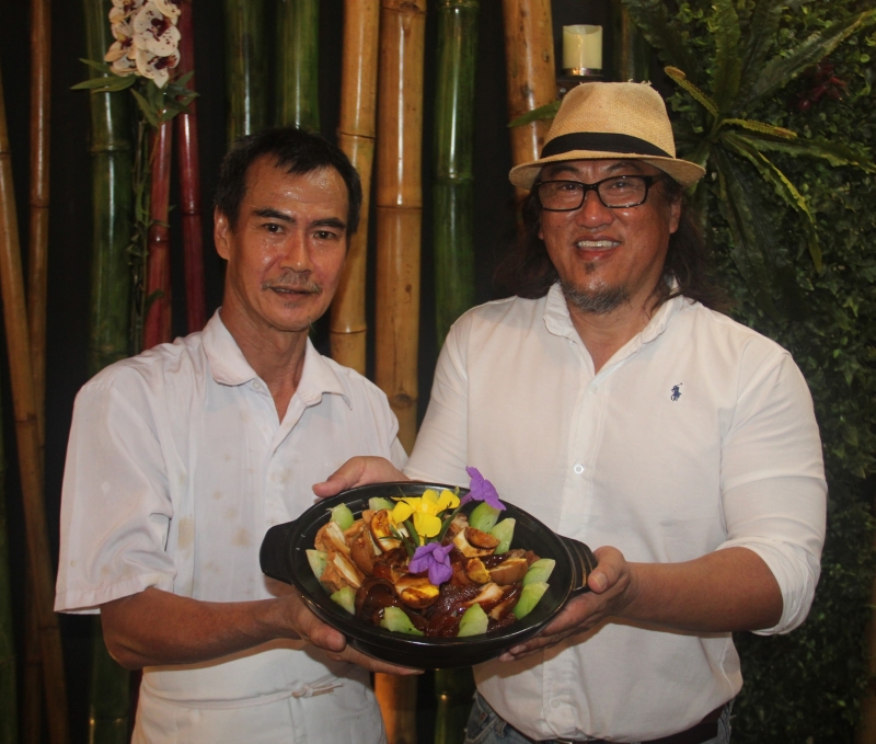 东主罗健昌（右）及主厨彭潮江向食客推荐卤味八宝锅。