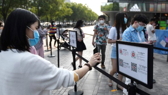 A woman uses a phone app to scan a code to prove her health and travel status before entering a shopping mall in Beijing. AFP